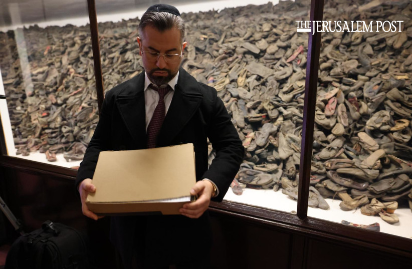 Eitan Neishlos holding shoe box in Auschwitz in front of children's shoes